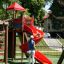 Children playing on a red spiral slide at a playground.