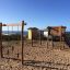 Lianes wooden playhouse on a beachside playground with climbing and sliding equipment.