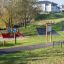 Playground with Diamond net climbing structure and pirate ship playset next to a paved path and gree