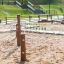 Adventure playground structure Gossamer with wooden posts and ropes in a sandy area.
