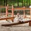 Child playing on Sahara wooden balance beam in forest playground