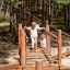 Wooden suspension bridge playground equipment Sahara with children playing outdoors in forested area