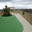 Green mounds on a rooftop playground with wooden structures and cityscape in the background, featuri