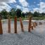 Wooden balance beam course Cape Code on gravel playground with green grass background.