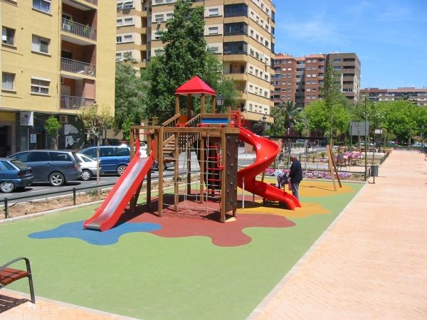 Playground with red slides and colourful Wetpour 80 flooring in an urban setting.