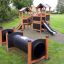 Knight's Castle Nature playhouse with slide and tunnels in a park.