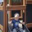 Child sliding down a slide of Knight's Castle Nature playhouse with slide.