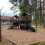 Knight's Castle Nature playhouse with slide in a wooded playground area.