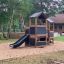 Knight's Castle Nature playhouse with slide in a forest playground