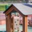 Fortress Nature playhouse with slide and climbing wall in a playground setting