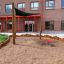 Square bench and table in a playground area outside a brick building.