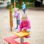 Girl sitting on Square bench and table in playground.