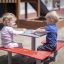 Children sitting at a square bench and table in a playground