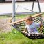 Child sitting on a Hammock in a playground.