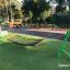 Green children's playground hammock set up on artificial grass.