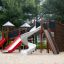 Mastodont castle with slide playground structure with red and white slides and climbing wall on sand