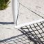 Hammock made of black rope tied to a white post on a sandy background.