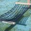 Black hammock net attached to wooden posts on grass.