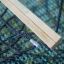 Wooden bar and rope of Hammock lying on a textured green surface.