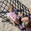 Two girls playing on a hammock at a playground.