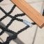 Hammock with black ropes and wooden bar.