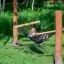 Child relaxing in black net hammock between wooden posts in green park