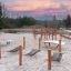 Hammock with wooden playground climbing structures on sandy ground at sunset