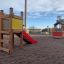 Wooden Toddler Tower Slide with red slide in playground.