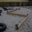 Classic Nature Trim Trail in a sandy play area with wooden balance beams and tire climbing obstacles
