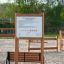 Rules Tab playground sign with usage regulations mounted on wooden frame in outdoor sandy play area