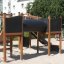 Playground structure Challenger Aztec Nature II with slides and climbing elements in a park setting.