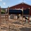 Challenger Aztec Nature II playground equipment with tunnel slide on sand near red building.