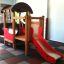 Locomotive with slide train playhouse in indoor play area with soft flooring.