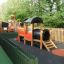 Locomotive with slide train playhouse in fenced playground area.