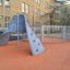 Aztec arch steel structure on an orange playground surface in an urban school setting.