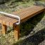 Gymnastic bench made of wooden slats with a metal handle in an outdoor setting.