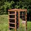 Wooden climbing box playhouse in a grassy outdoor area.