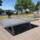 Concrete table tennis, free-standing on outdoor patio near water.