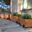 Three Wooden flowerpot II planters with flowers, outside a house.