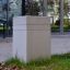 Concrete Brno block placed on grass in front of a modern building.