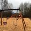 Swing Frame (double swing) on a playground with wood chips and a slide in the background