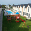 Double swing set with wooden frame and red slide.