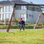 Child playing on Swing Frame (double swing) in a grassy backyard.