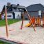 Double swing set in a playground with climbing structure.