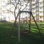 Swing Frame (single swing) in a playground area with residential buildings in the background.
