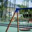 Single swing frame with wide seat in outdoor playground.