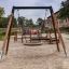 Single swing with wide swing frame in playground.