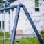 Swing Metal Frame (single swing, wide) in outdoor setting with blurred white building in background.