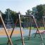Swing seat: Safety seat on a playground with climbing structure and other play equipment in the back