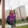 Girl sitting on a Tire seat swing in a playground.